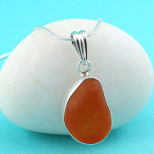 We've never seen a sea glass gem quite like this one--a very old, extremely rare sea glass specimen in an unusual orange/red color. We had it bezel set in sterling silver to protect its value. We believe that this sea glass is from an antique orange/red electrical insulator, well over 100 years old, probably from the thick top part of the insulator. There is a perfect home for this rare orange/red sea glass pendant necklace and it will be the home of a true sea glass aficionado. Genuine sea glass jewelry from full time sea glass jewelry artisan. We guarantee all work and offer free gift wrapping and free shipping services.  You may choose the length of your top quality 2.2mm sterling silver bead necklace. Metal: Sterling Silver Bezel Setting and Necklace Origin of Glass: Nova Scotia Rarity: Extremely Rare Size of Sea Glass: 1" Long, 3/4" Wide and 1/2" Thick Size of Pendant: 1-1/2" Long, 3/4" Wide and 1/2" Thick [cc_product sku="n144" display="inline" quantity="true" price="true"]